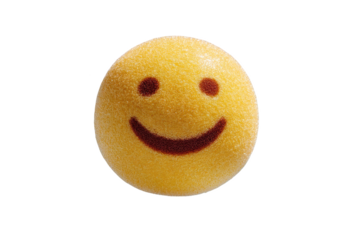 Yellow candy with brown smiley face on black background close up studio shot
