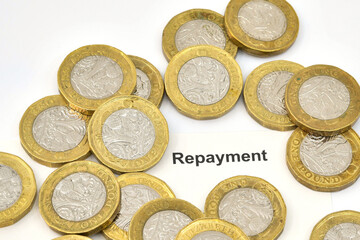 Close up view of a repayment slip surrounded by British one pound coins. Finance and loans concept.