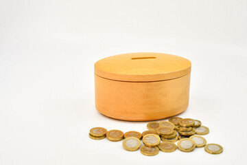 One pound coins alongside a wooden money box. Savings concept. No people.