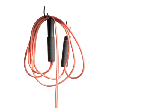 Pink jump rope with black handles hanging, ready for a workout against black background