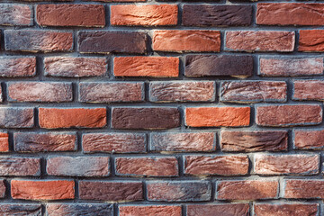 Textured brick wall with a mix of red and brown tones in urban setting