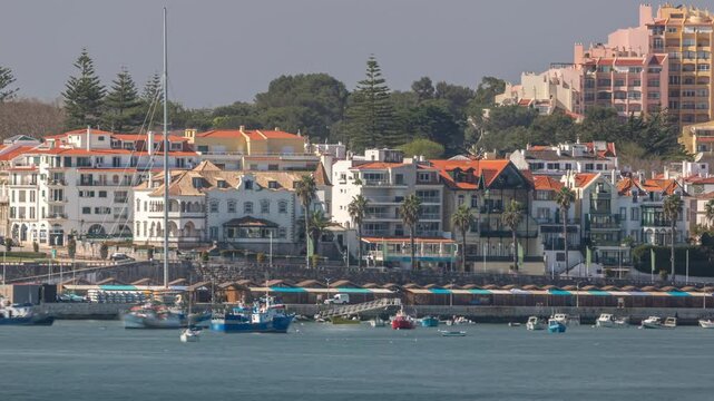 Boats and yachts floating on the water of Cascais bay with Palacete Seixas. Timelapse showcasing the scenic waterfront, historic architecture and coastal charm with houses and cranes in the background