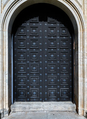Old black wooden door in the arch of a building. Close up view