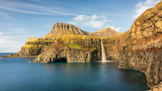 Animated photo of Faroe Islands. Island of Vagar: Village Gasadalur, waterfall Mulafossur and rainbow above North Atlantic ocean. Denmark.  4K, motion. For holidays and travel, tourist advertising