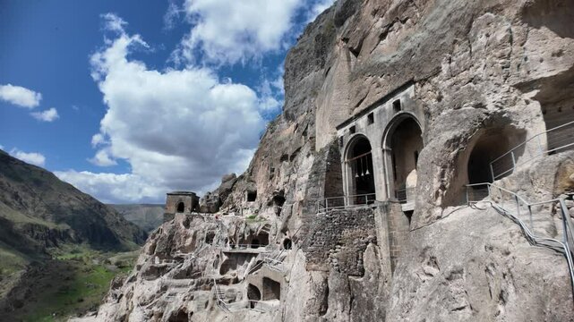 Vardzia, a 12th-century cave monastery carved into Erusheti cliffs, displays ancient architecture against a cloudy sky, reflecting medieval ingenuity and religious heritage