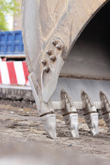 Close-up of excavator bucket. Excavator levels the ground on the site. Repair work in the city....