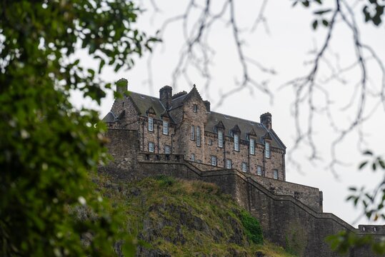 Edinburgh, United Kingdom - August 28th 2023: Edinburgh Castle seen from afar, framed by trees. 