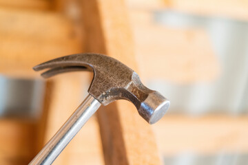 Construction hammer, Close-up on a metal hammer with wood structure in background.