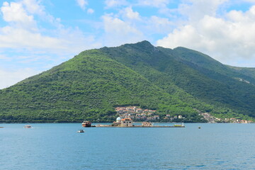Fototapeta premium PERAST, MONTENEGRO - MAY 06 2024: Tourists are relaxing on the sea and walking on the street, on May 06, 2024 in Perast, Montenegro. During spring on a sunny day.