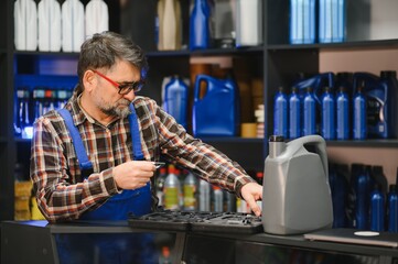 Salesman holding tool and choosing engine oil in auto parts store