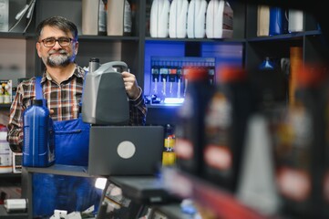 Salesman holding engine oil bottles in auto parts store