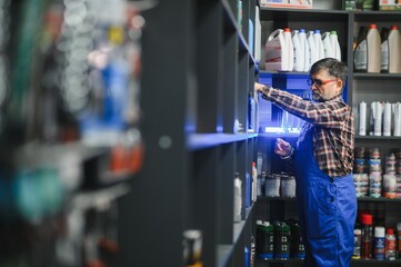 Salesman arranging motor oil bottles on shelf in auto parts store