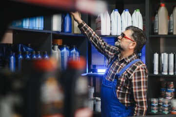 Salesman picking motor oil bottle in auto parts store