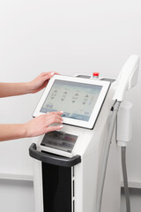 Young woman cosmetologist using modern laser platform in clinic. Ultrasound device for improving skin tone and texture, photorejuvenation system