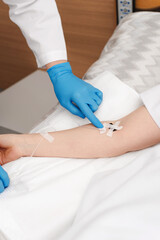 Woman hands in sterile gloves install a catheter for intravenous administration of drugs to a patient. Doctor putting a drip to a patient for intravenous therapy