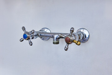 Wall mounted metal faucet with two cross handles for hot and cold water, spout has been removed...