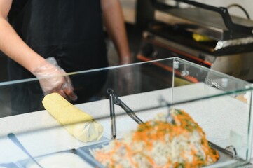 Chef preparing shawarma or kebab with salad and lavash in a street food stall
