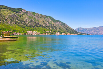 Obraz premium Kotor Montenegro, May 11, 2024: The Bay of Kotor and boats and the mountainous background. The Adriatic Sea Coast on a sunny, hot, Spring Afternoon.