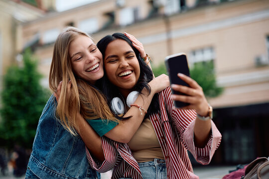 Happy female friends having fun while taking selfie with mobile phone. - Powered by Adobe