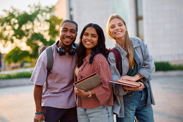 Group of happy students at university campus looking at camera.