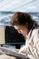 Management executive looking over paperwork in server farm to ensure compliance with industry...