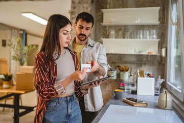 couple stand in the kitchen and use digital tablet for online shopping