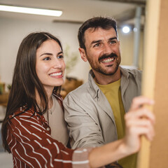 A couple examines a framed painting and chooses a place for it
