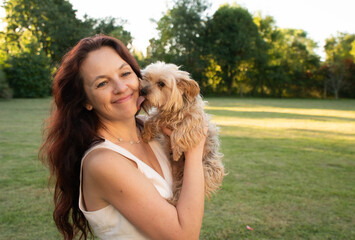 A woman is holding a dog in a park