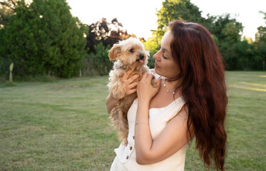 A woman is holding a dog in a park