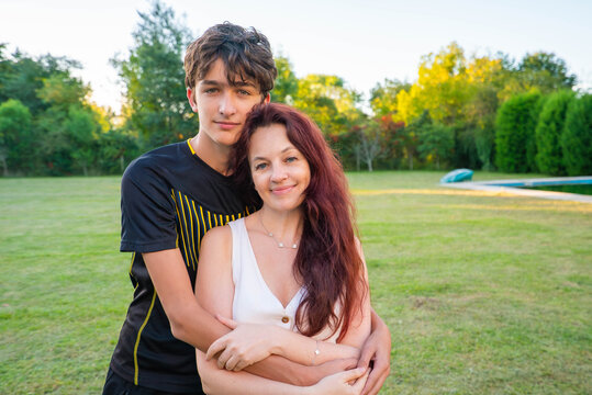 A young son and Mother are standing in a grassy field.