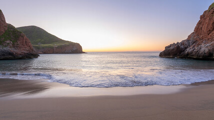 Beautiful tranquil beach with calm waters and mountains during a stunning sunset moment