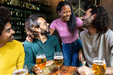 Group of young multiracial happy people drinking beer and talking in a pub, enjoying happy hour. Friendship concept