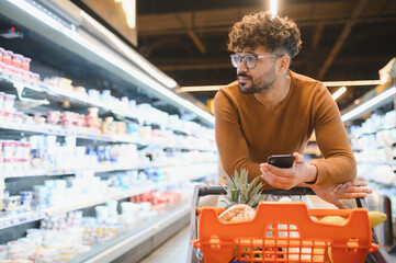 Customer using smartphone while shopping groceries in supermarket