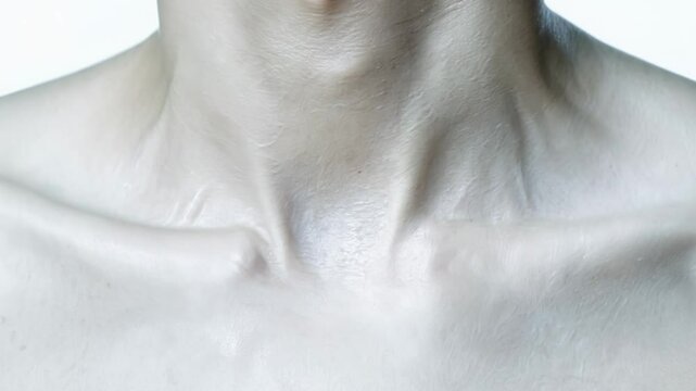 close-up video of a human neck showing a subtle pulse under high key clinical lighting, with a subtle pan. medical or health concept