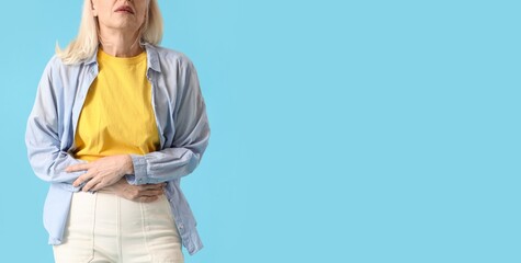 Mature woman suffering from menstrual pain on light blue background with space for text
