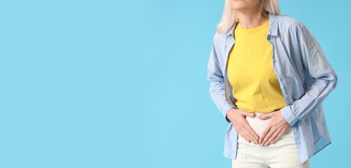 Mature woman suffering from menstrual pain on light blue background with space for text