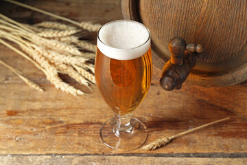 Oak barrel and glass of cold beer on wooden background