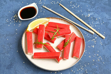 Plate with tasty crab sticks on blue background © Pixel-Shot