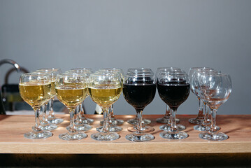 Wine Glasses with Red and White at Event Bar. Rows of wine glasses filled with red and white wine arranged on a wooden counter, ready for serving at a celebration.