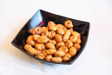 Close-up of a black bowl filled with golden-brown Italian taralli crackers, served as a savory snack or appetizer.