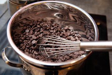 Melting Dark Chocolate Chips in Saucepan. Close-up of dark chocolate chips in a metal pot with a...