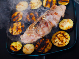 Closeup of appetizing slice of pork shoulder roasted with eggplants in fry pan. Cooking at home