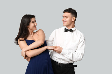 Happy young couple dancing on grey background