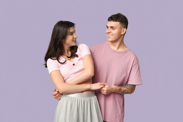 Beautiful young couple dancing on lilac background