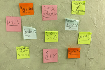 Colorful sticky notes with written words on grey grunge background. Sex education
