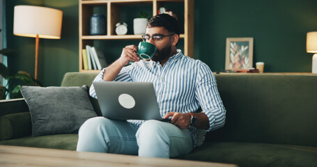 Man, drink and coffee with laptop at house for morning start, research and schedule update of article. Male person, beverage and online information, reading feedback and editing story for publication