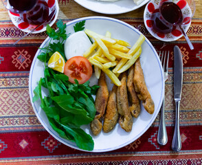 Portion of fried red mullet served with french fries, lemon and greens, typical dish of Turkey