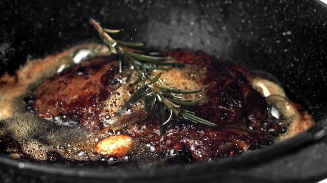 Beef steak in a pan with garlic and spices. Filmed on a high-speed camera at 1000 fps. High quality FullHD footage