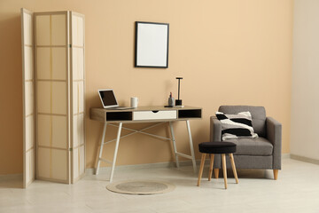 Interior of stylish office with workplace, folding screen, armchair and coffee table