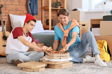 Male students eating pizza in dorm room on moving day